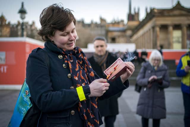 Anna Jakubova sets fire to her Russian passport during the Standing In Solidarity With Ukraine vigil