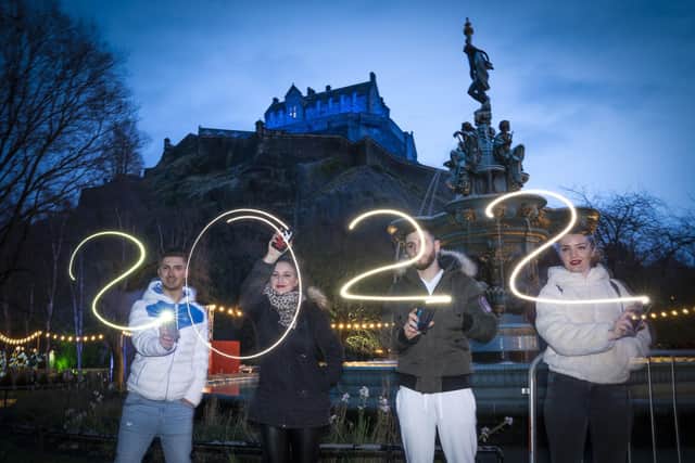 Alex Badea, Maria Mutuliga, Livia Miheala and Alex Rudolff, from Dorset, use their smartphones to spell out 2022 in Edinburgh's Princes Street Gardens during New Year's Eve.