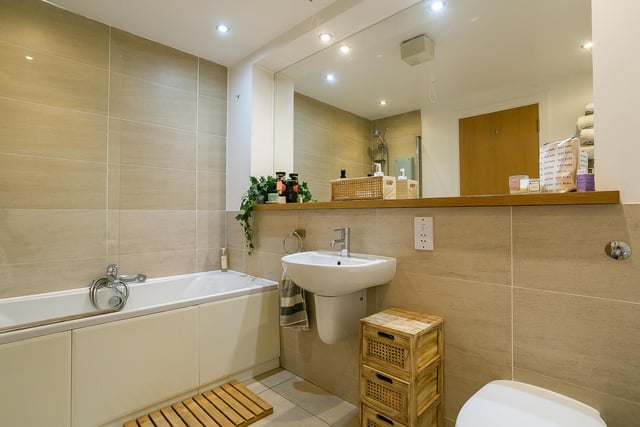 The family bathroom, accessible from the hall, includes a three-piece suite, a shower-over-bath, a chrome, ladder-style radiator, and elegant tiled splash walls.