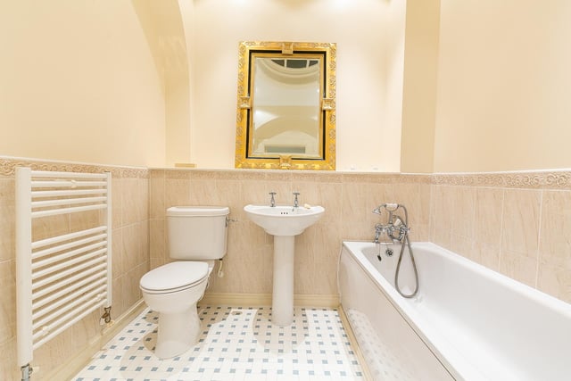 The family-size bathroom is fitted with a contemporary three-piece suite, partially tiled splash walls, a ladder-style radiator and an ornate skylight window.