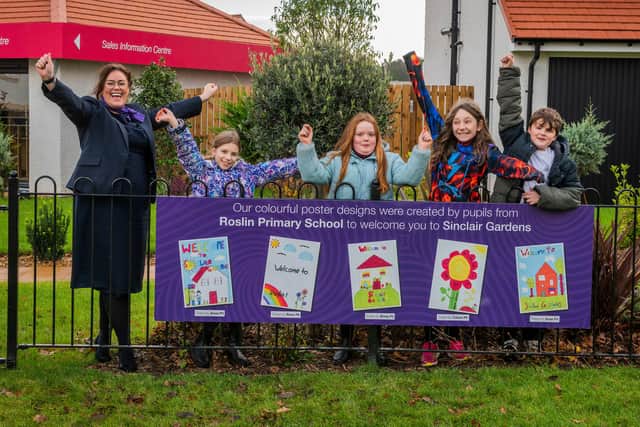 Pupils at Sinclair Gardens in Roslin, pictured with the winning flag designs, alongside Taylor Wimpey East Scotland’s sales executive Linzi McEwan. Photo - Chris Watt.