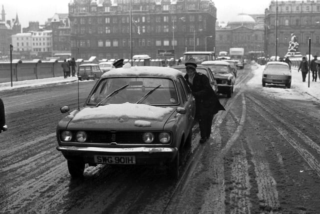 A kind traffic warden pushes a car on North Bridge during the blizzards in Edinburgh, January 1978.