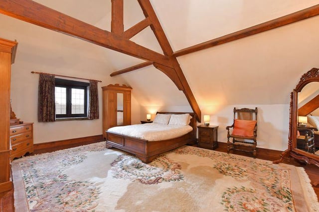 The master bedroom is built into the roof space with a high ceiling with exposed timbers, and a rear window with a stone window sill.