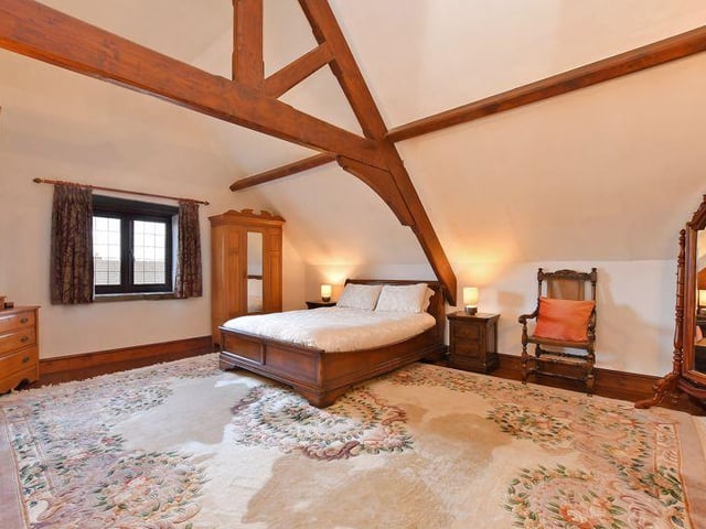 The master bedroom is built into the roof space with a high ceiling with exposed timbers, and a rear window with a stone window sill.