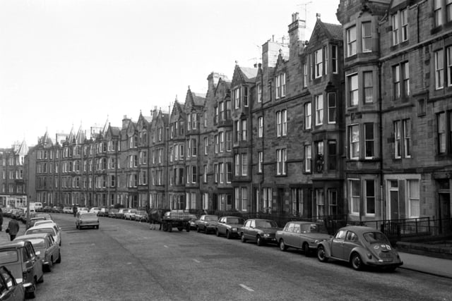 Tenement flats in Warrender Park Road, in the Marchmont area of Edinburgh, with cars parked along the street and a horse and cart delivering milk in December 1981.