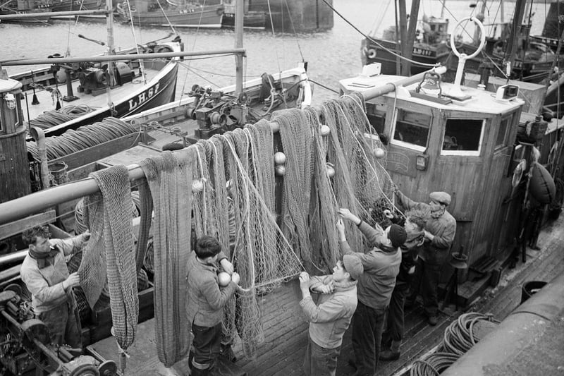 Fishermen home for New Year tidy up their nets and prepare to leave their boats at Port Seton Harbour, 1960s