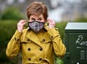 First Minister and leader of the SNP Nicola Sturgeon puts on a mask following a visit to Burnside chemist during campaigning in Rutherglen. Picture: Jeff J Mitchell/Getty Images