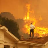 A man watches the approach of a wildfire from the roof of his house near Camarillo, California (Picture: David McNew/Getty Images)