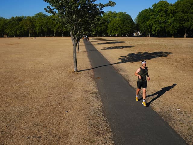 A jogger runs along a path next to sun scorched grass in London's Victoria Park