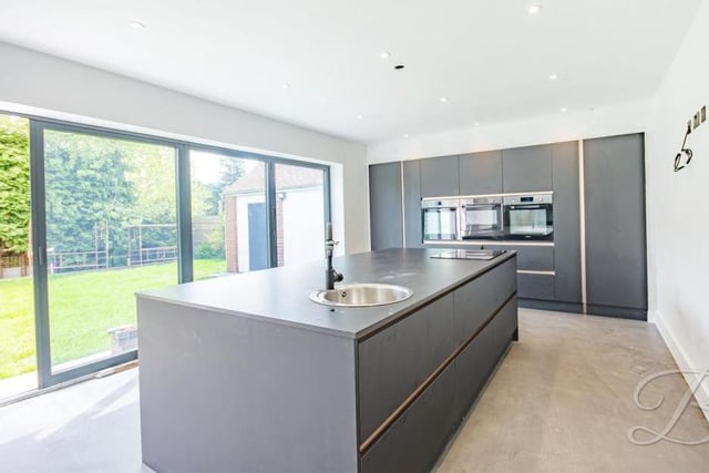 The stunning kitchen has a great sense of space, thanks to its open-plan layout. It comes complete with a range of sleek wall and base units, and an island, plus integrated appliances and bi-folding doors, which can be opened up on a warm summer's day.