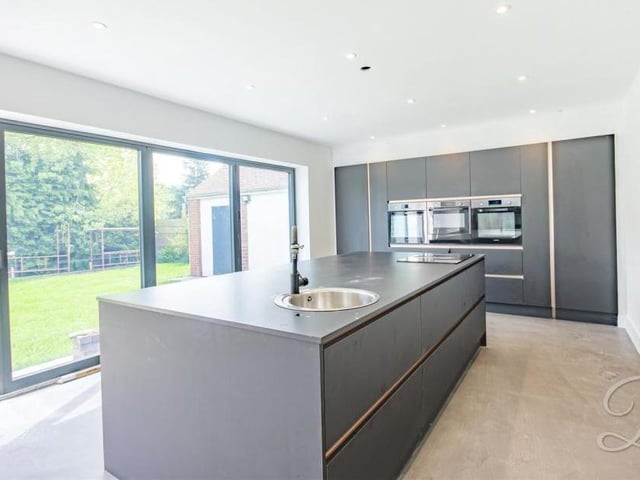 The stunning kitchen has a great sense of space, thanks to its open-plan layout. It comes complete with a range of sleek wall and base units, and an island, plus integrated appliances and bi-folding doors, which can be opened up on a warm summer's day.