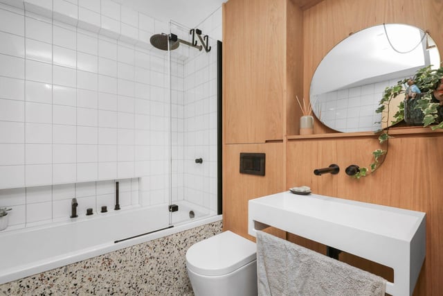 The family bathroom, comprising double end bath with shower over, wash hand basin and contrasting oak feature wall above wc, mirrored in the window recess.