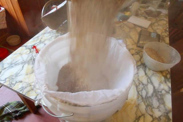 Pouring the grains into the muslin bag inside bucket one which should be inside bucket two at this point. Hold your breath, it gets a little dusty.