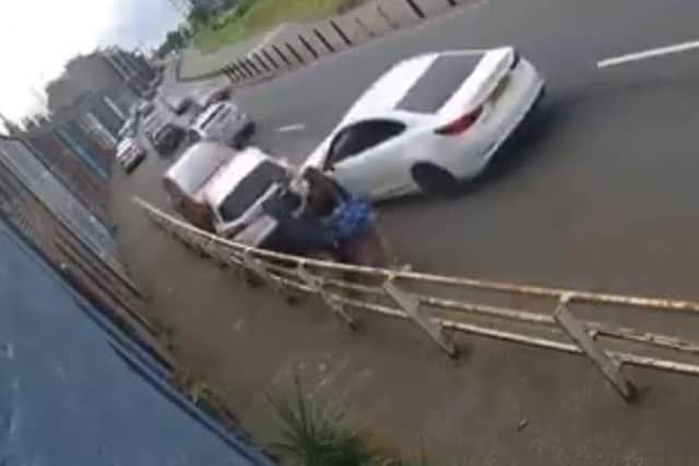 The car narrowly misses pedestrians as it collides with the first vehicle.