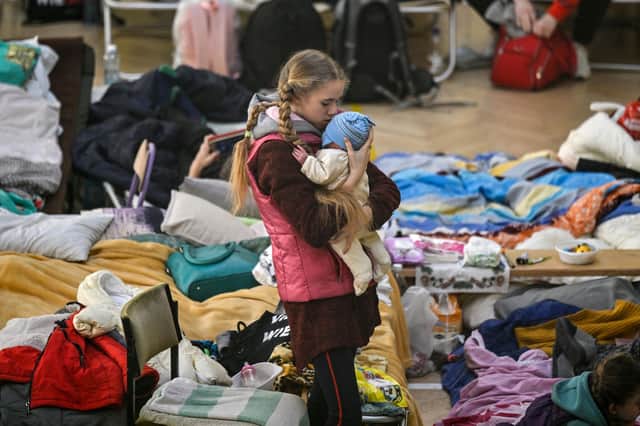 A girl holds her sibling in a temporary shelter for Ukrainian refugees at a school in Przemysl, near the Ukrainian-Polish border (Picture: Louisa Gouliamaki/AFP via Getty Images)
