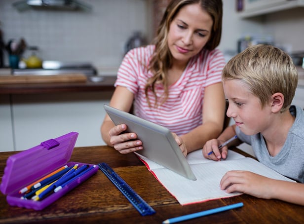 Mother using a digital tablet while helping son with his homework at home