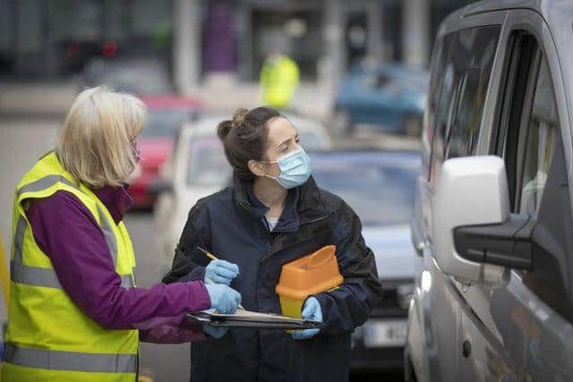 A nurse and volunteer talk to patients in their vehicle at one of the new the drive-thru flu clinics at Little France, Edinburgh.