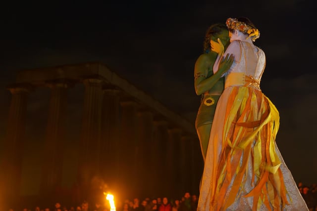 Two performers embrace as they celebrate the arrival of summer, at the peak of Edinburgh's Calton Hill.
