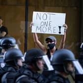 A protester holds a sign as police in riot gear move down the street in formation in Louisville, Kentucky (Photo: Brett Carlsen/Getty Images)