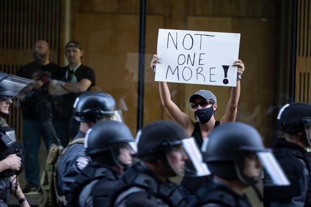 A protester holds a sign as police in riot gear move down the street in formation in Louisville, Kentucky (Photo: Brett Carlsen/Getty Images)