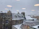Snow is blanketing the rooftops and roads in Edinburgh