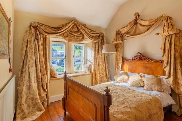 Swathes of mterial above  the bed and window bring a dramatic look to the bedroom. There are window seats, stone mullioned windows and original oak flooring in both bedrooms.