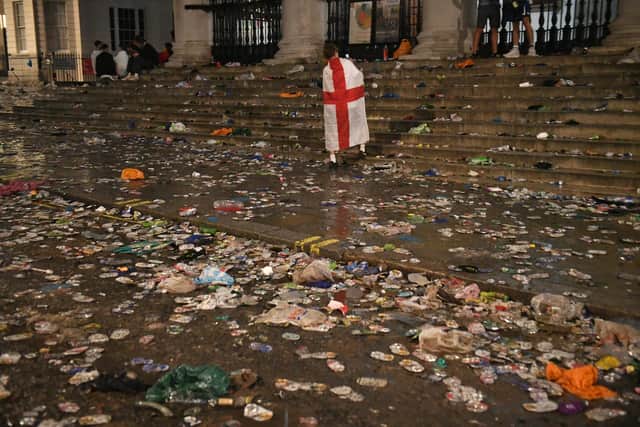 A lone fan walks amongst litter strewn on the ground in front of St Martin-In-The-Fields church in Trafalgar Square, London, after Italy beat England on penalties to win the Euro 2020 final (Picture: Dominic Lipinski/PA)
