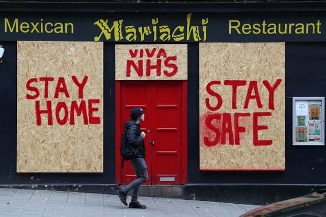 A person passes a boarded up restaurant in Edinburgh which has been painted with an NHS supporting message as the UK continues in lockdown to help curb the spread of the coronavirus.