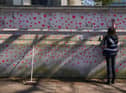A woman painting red hearts on the COVID-19 Memorial Wall opposite the Houses of Parliament at Embankment, central London, in memory of the more than 145,000 people who have died in the UK from coronavirus. PA.