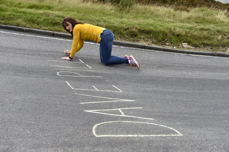 A member of the public writes on the road on the Cairn Ô O Mount prior to riders passing by during stage eight.