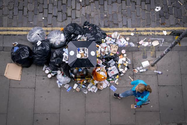 A member of the public walks past a bin and litter in Victoria Street in Edinburgh city centre.