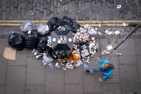 A member of the public walks past a bin and litter in Victoria Street in Edinburgh city centre.