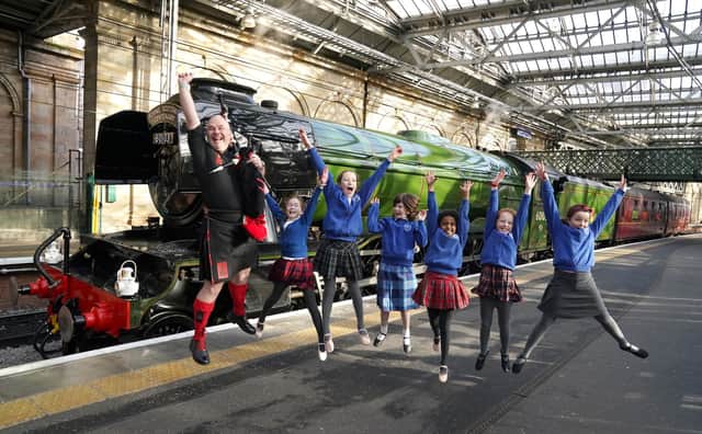 Piper Kevin MacDonald from the Red Hot Chilli Pipers with schoolchildren from Morningside Primary School and the Royal Scottish Country Dance Society beside Flying Scotsman at Edinburgh Waverley on Friday. Picture: Andrew Milligan/PA Wire