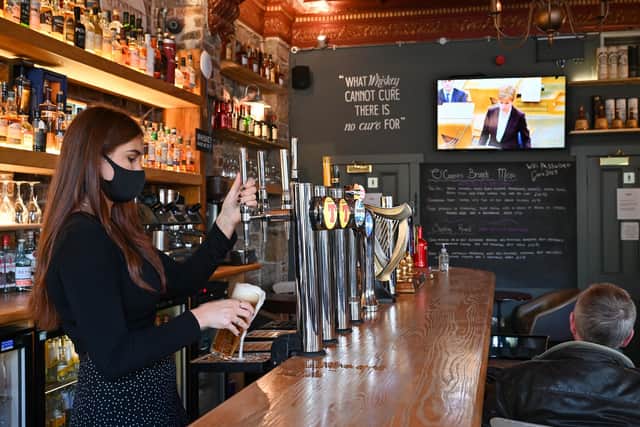 A pub staff member wearing a mask in Edinburgh. Photo by Jeff J Mitchell/Getty Images