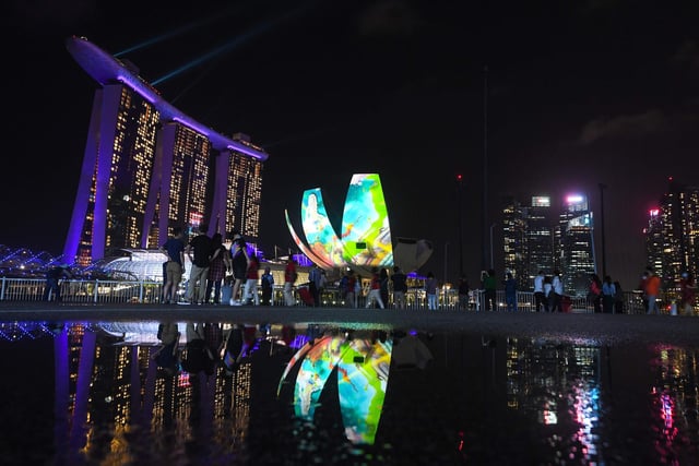 People watch as the Marina Bay area is lit up as part of New Year's Eve celebrations in Singapore on December 31, 2020.