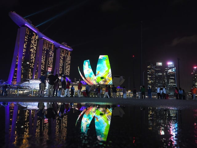 People watch as the Marina Bay area is lit up as part of New Year's Eve celebrations in Singapore on December 31, 2020.