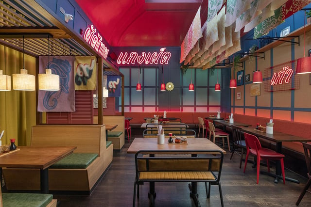 The interiors recall Bangkok’s thriving cafe culture and the dazzle of a Thai evening out with intimate booth seating, vibrant neon lights and red pendants hanging from the double-height ceiling.