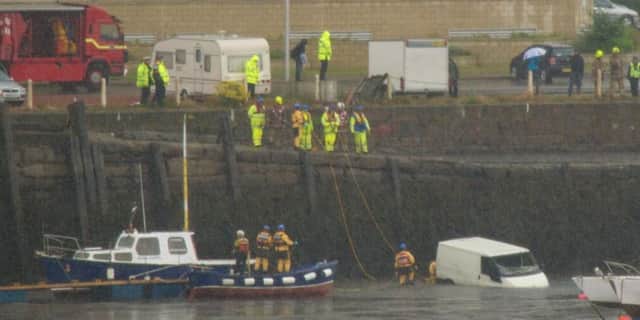 Emergency workers on Granton Harbour haul the van, bottom right, out of the water. Picture: James Cocker