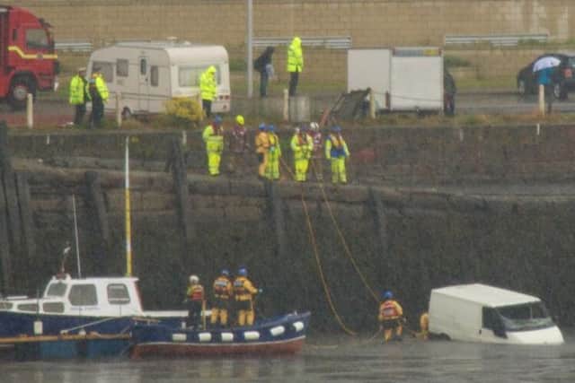 Emergency workers on Granton Harbour haul the van, bottom right, out of the water. Picture: James Cocker