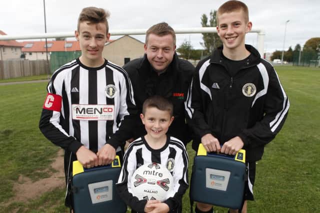 Players Leon Stewart, eight, captain Jake Beveridge, 14, and Mattie Beatie, 14, are joined by Phil Menzies, whose firm donated money for one of the defibrillators. Picture: Toby Williams