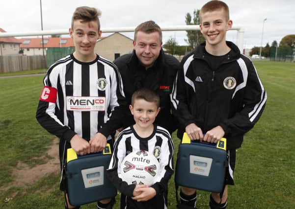 Players Leon Stewart, eight, captain Jake Beveridge, 14, and Mattie Beatie, 14, are joined by Phil Menzies, whose firm donated money for one of the defibrillators. Picture: Toby Williams