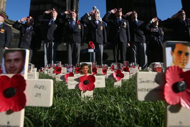 Standard bearers stand to attention while Royal Engineer veterans salute crosses bearing pictures of service personnel killed in Afganistan. Picture: PA