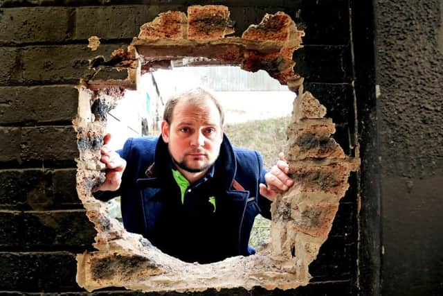 Matt Lopata beside the hole in the wall at the rear of the building. Picture: Gordon Fraser