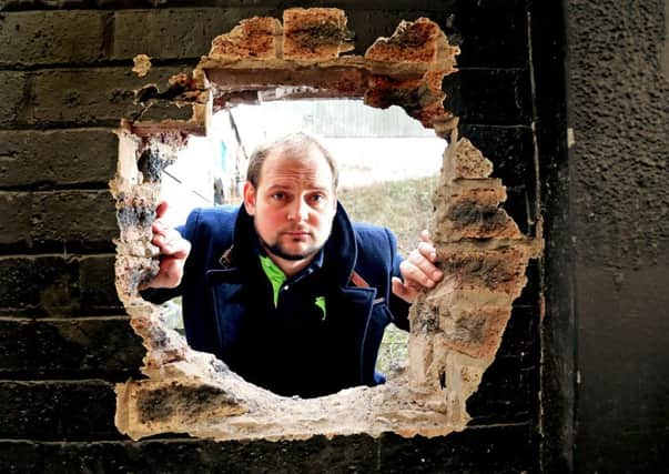 Matt Lopata beside the hole in the wall at the rear of the building. Picture: Gordon Fraser