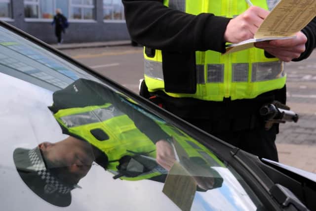 Pc Daniel Halliday tickets a motorist parked in a disabled parking bay at the Lasswade Centre. Picture: Lisa Ferguson
