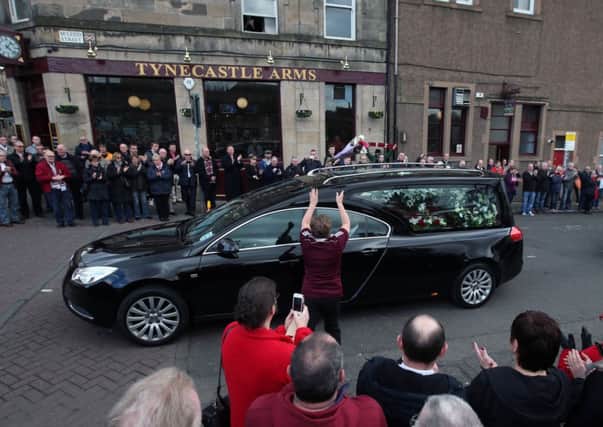 Crowds line the streets as the hearse carrying the coffin of Dave Mackay leaves Tyncastle Stadium. Picture: PA