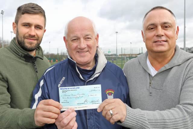 Jamie Skinner's brother Tony, left, and dad George, right, accept the cheque from Tynecastle FC chairman Douglas Dalgleish. PIcture: Gordon Fraser