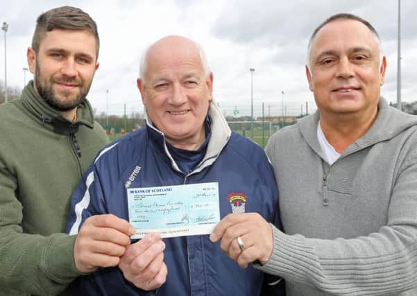 Jamie Skinner's brother Tony, left, and dad George, right, accept the cheque from Tynecastle FC chairman Douglas Dalgleish. PIcture: Gordon Fraser