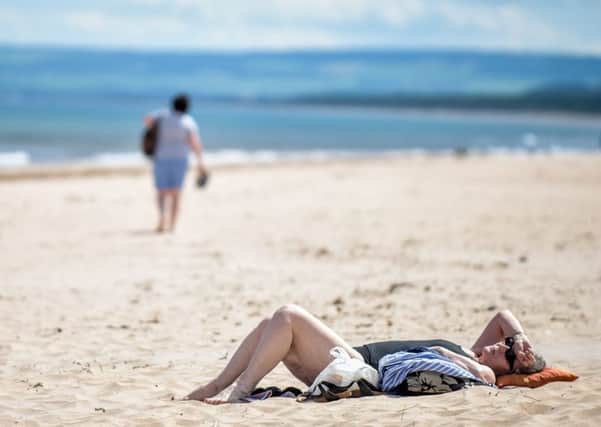 A woman sunbathes on East Beach in Lossiemouth today. Picture: Hemedia