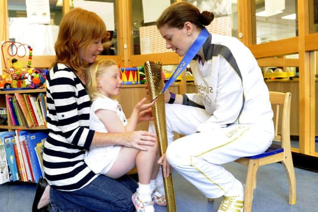 Katie Ford shows the Olympic torch to six-year-old Rachel Macleod with mum Helen at the Sick Kids. Picture: Esme Allen